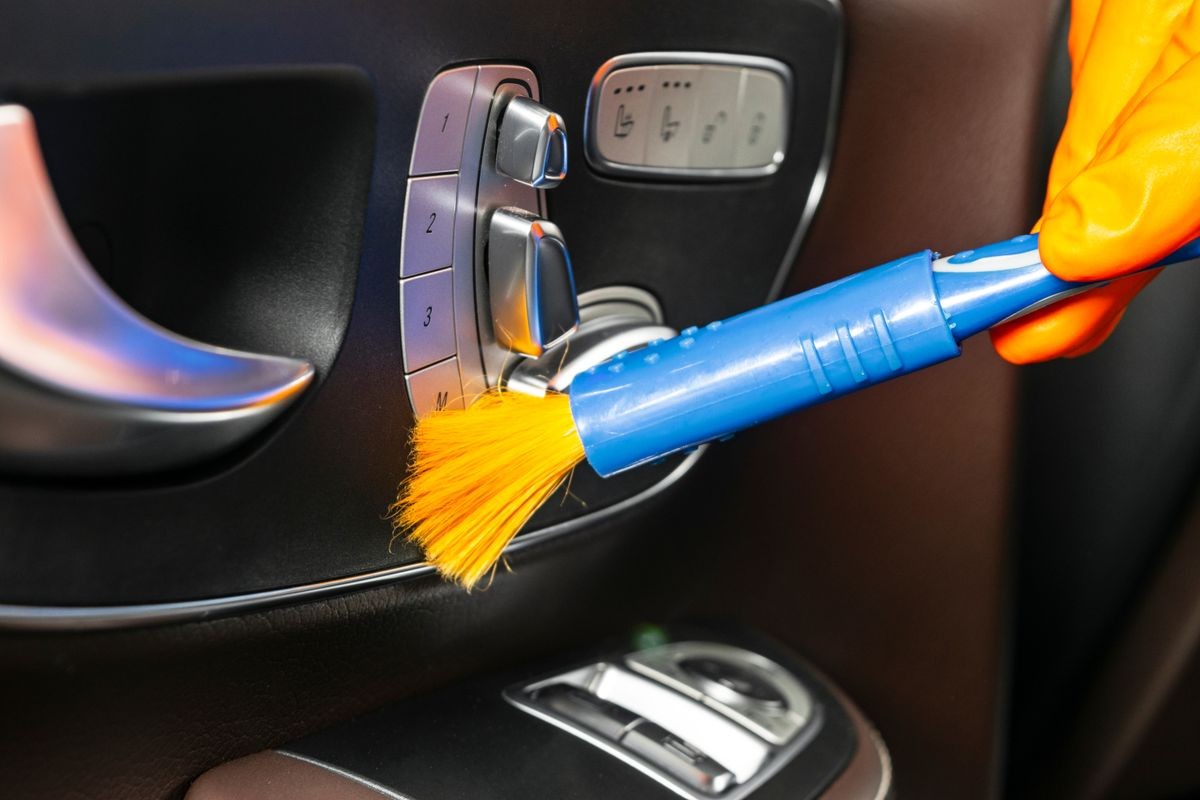 A man cleaning car with cloth and brush. Car detailing. Selective focus. Car detailing. Cleaning with brush. Worker cleaning. Brush and cleaning solution to clean.