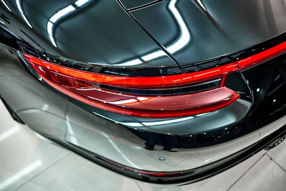 Taillight detail of black car. Close up of modern sportscar Tail-light. Top view shot of rear side of vehicle. Illustration of brake light design in the back of automibile. Sports car background